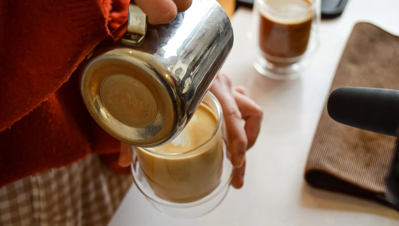 Barista pouring coffee at Nook coffee shop and wine bar in De Pijp.