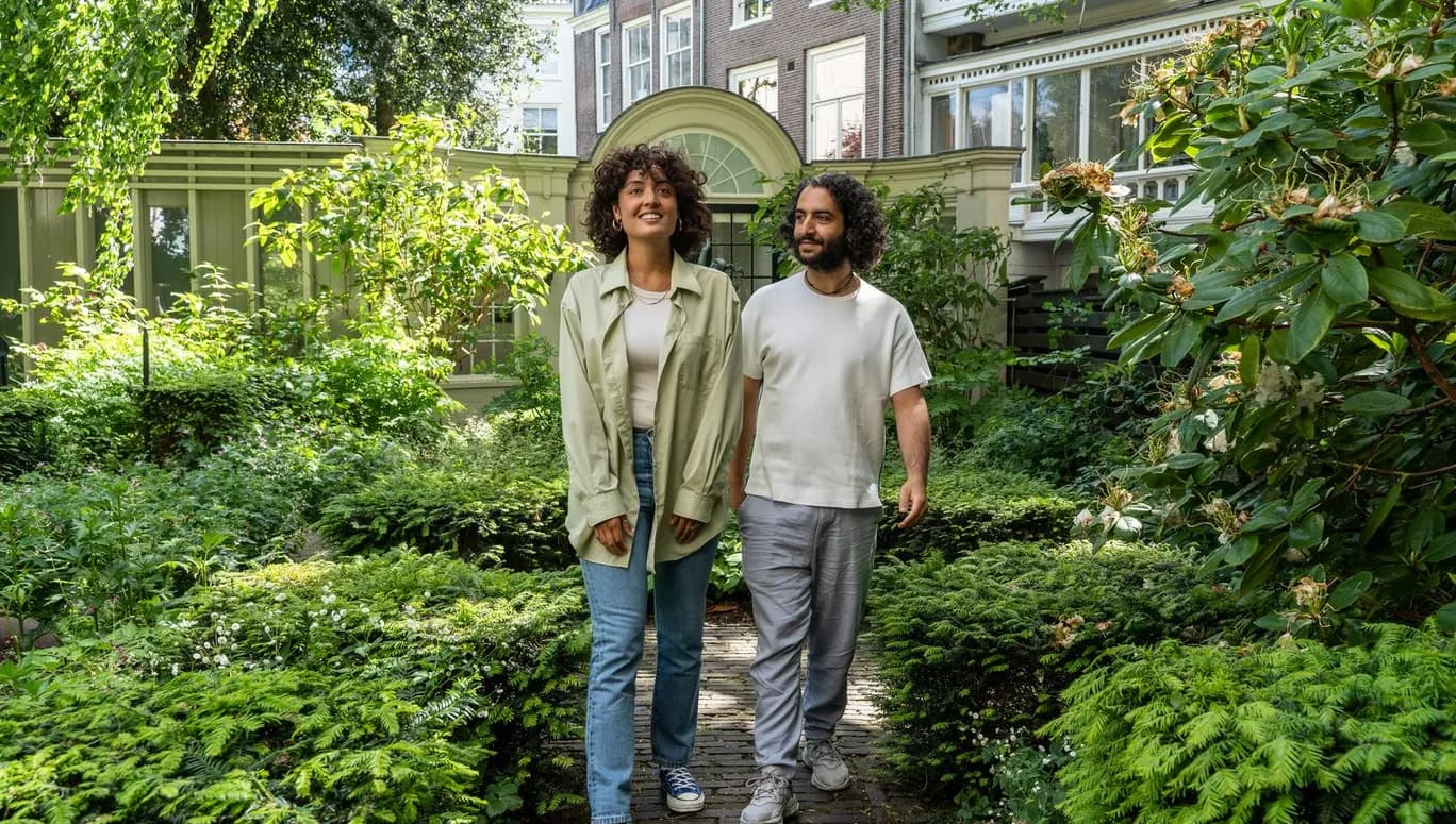 A couple walks trough the garden of Huis Marseille.