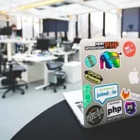 Laptop with Startup Amsterdam sticker and other stickers on desk in office