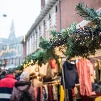 Christmas market in Haarlem. With a close-up of a pine branch covered in Christmas lights with a market and church tower in the background.