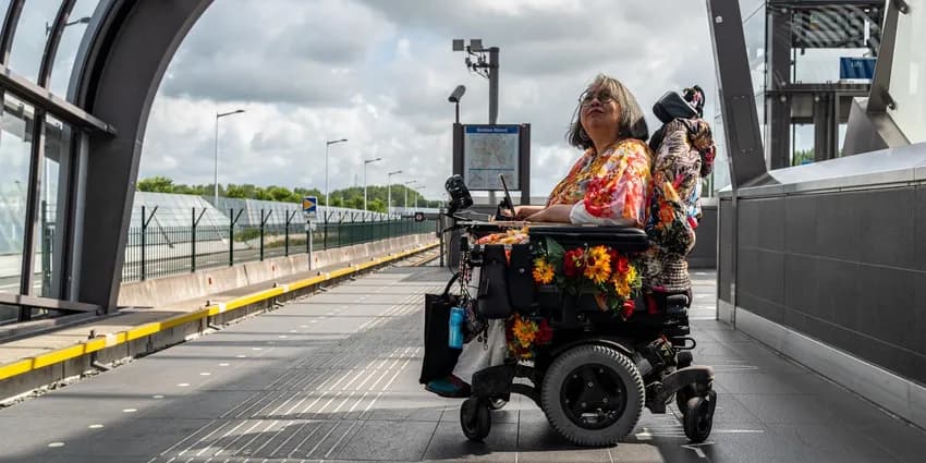 A person in an electric wheelchair on the platform waiting for the metro.