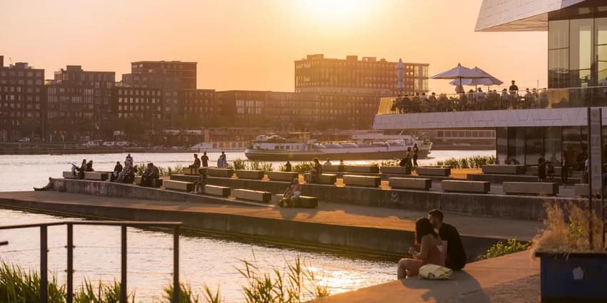 People enjoy the sunset at IJ-boulevard near EYE Filmmuseum.