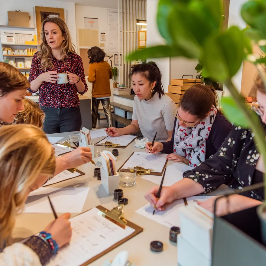 People taking a Calligraphy workshop writing on a clipboard paper holder