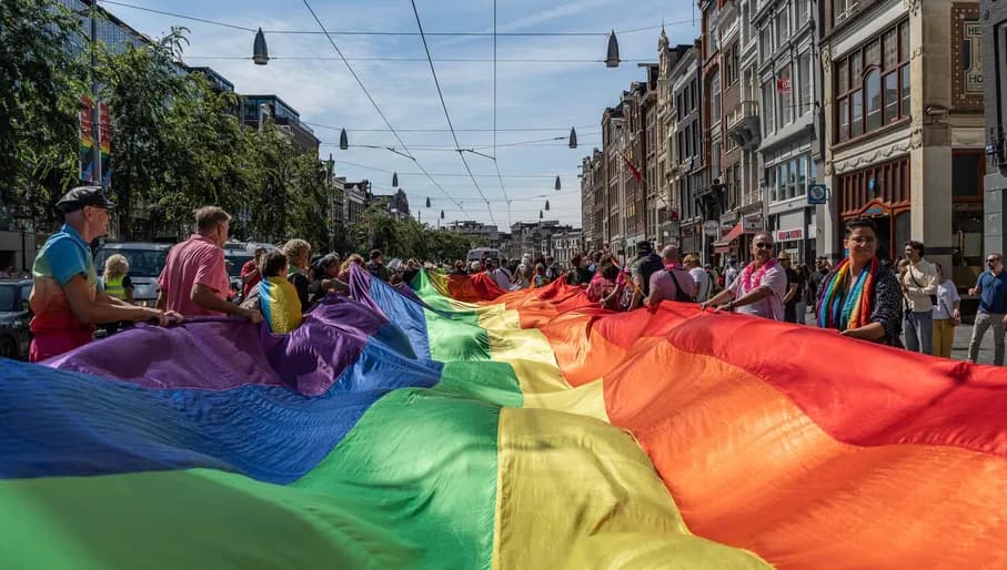 A crowd of people marching with a pride flag.