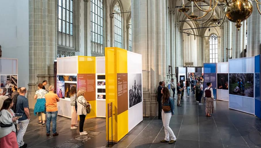 Visitors looking at photos in exhibition at World Press Photo 2023 in De Nieuwe Kerk