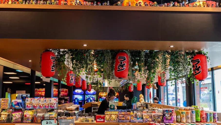 Arcade with anime interior, design and toys and gifts. People preparing good at the ramen bar, candy, asian interior and toys on the bar