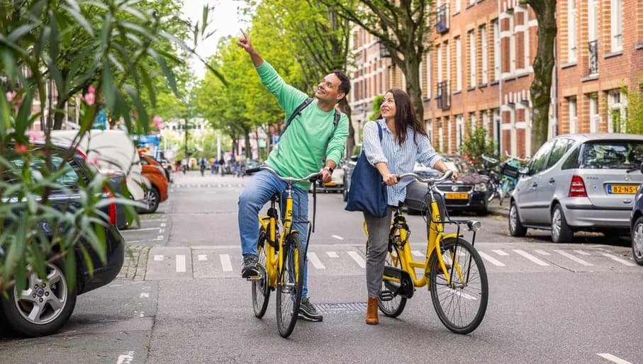 A couple on rental bikes from Yellow Bike cycle through Bosboom Toussaintstraat.