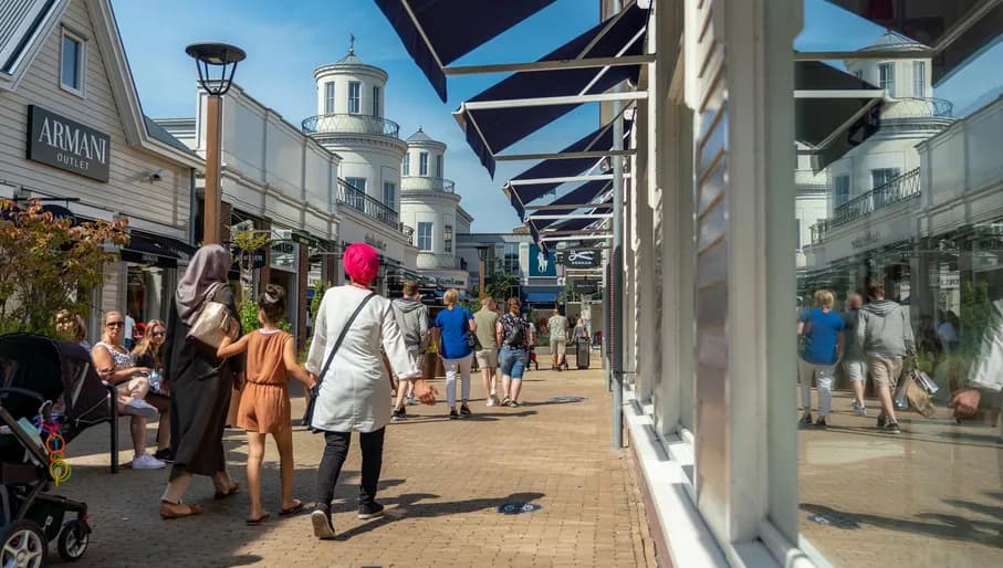People holding hands and  walking in the Bataviastad Outlet - Shop street